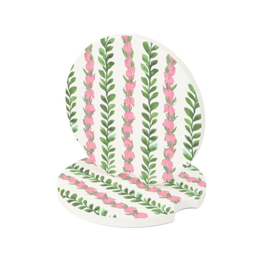 two circular car coasters featuring a repeatingHawaiian flower lei pattern of pink flowers and green leaves.