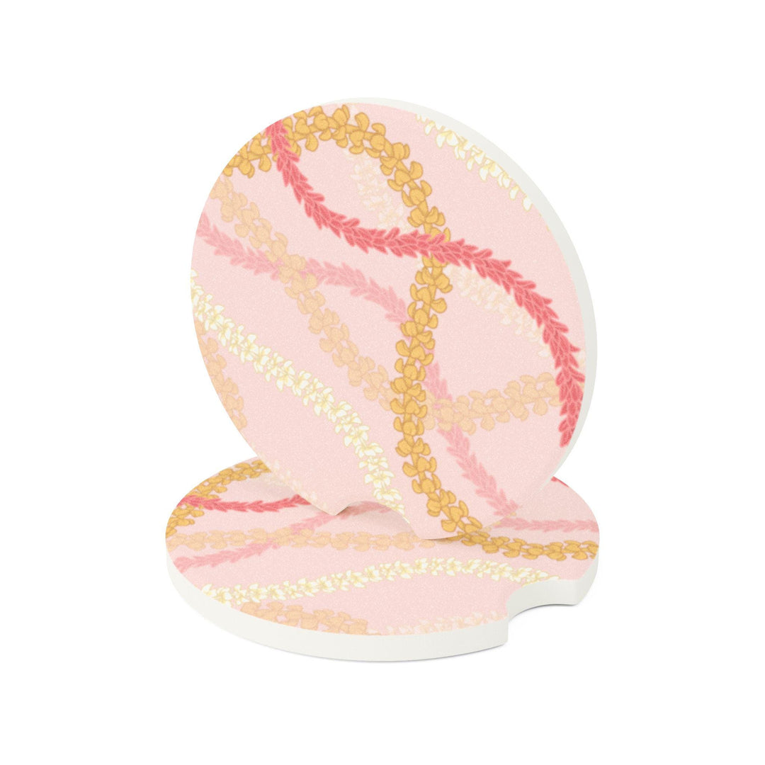 a car's cup holder with two circular coasters featuring a floral Hawaiian flower lei pattern in shades of pink and yellow.