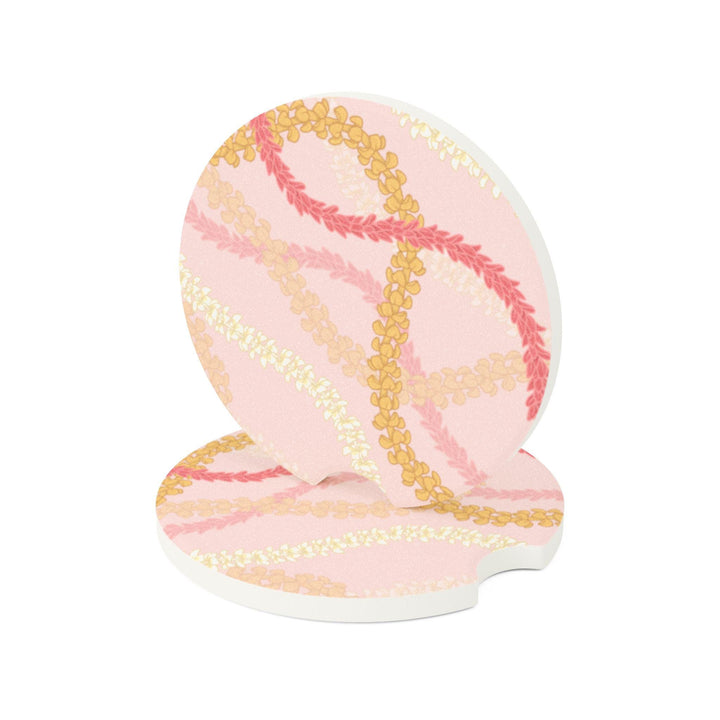 a car's cup holder with two circular coasters featuring a floral Hawaiian flower lei pattern in shades of pink and yellow.