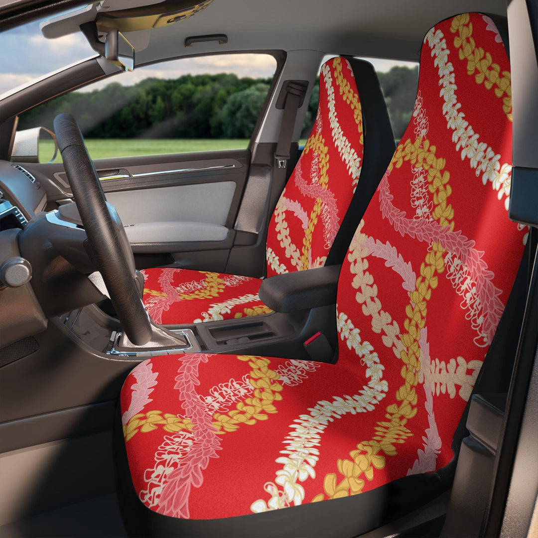 the interior of a car with a set of red front car seat covers featuring a Hawaiian floral pattern in yellow and white.