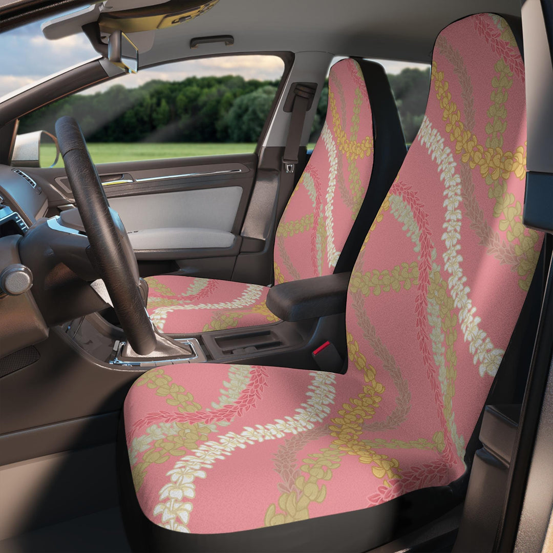 the interior of a car with a Hawaiian flower lei pink and yellow floral patterned front car seat covers on the driver's seat and a matching seat cover on the passenger seat.