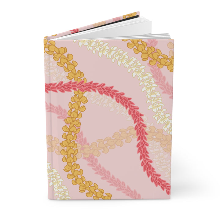a pink notebook with a floral pattern of yellow and white flowers on the cover.