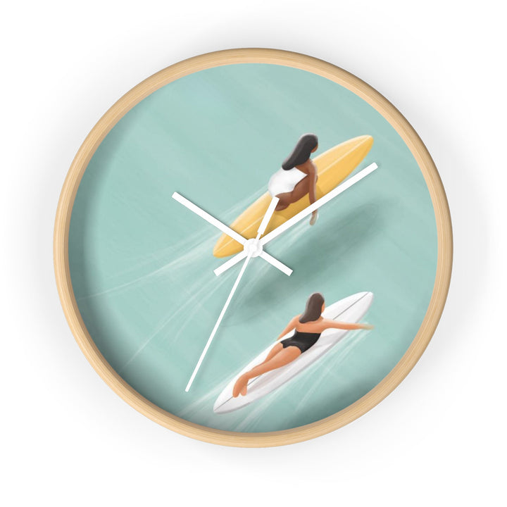A wall clock with a design depicting two women surfing