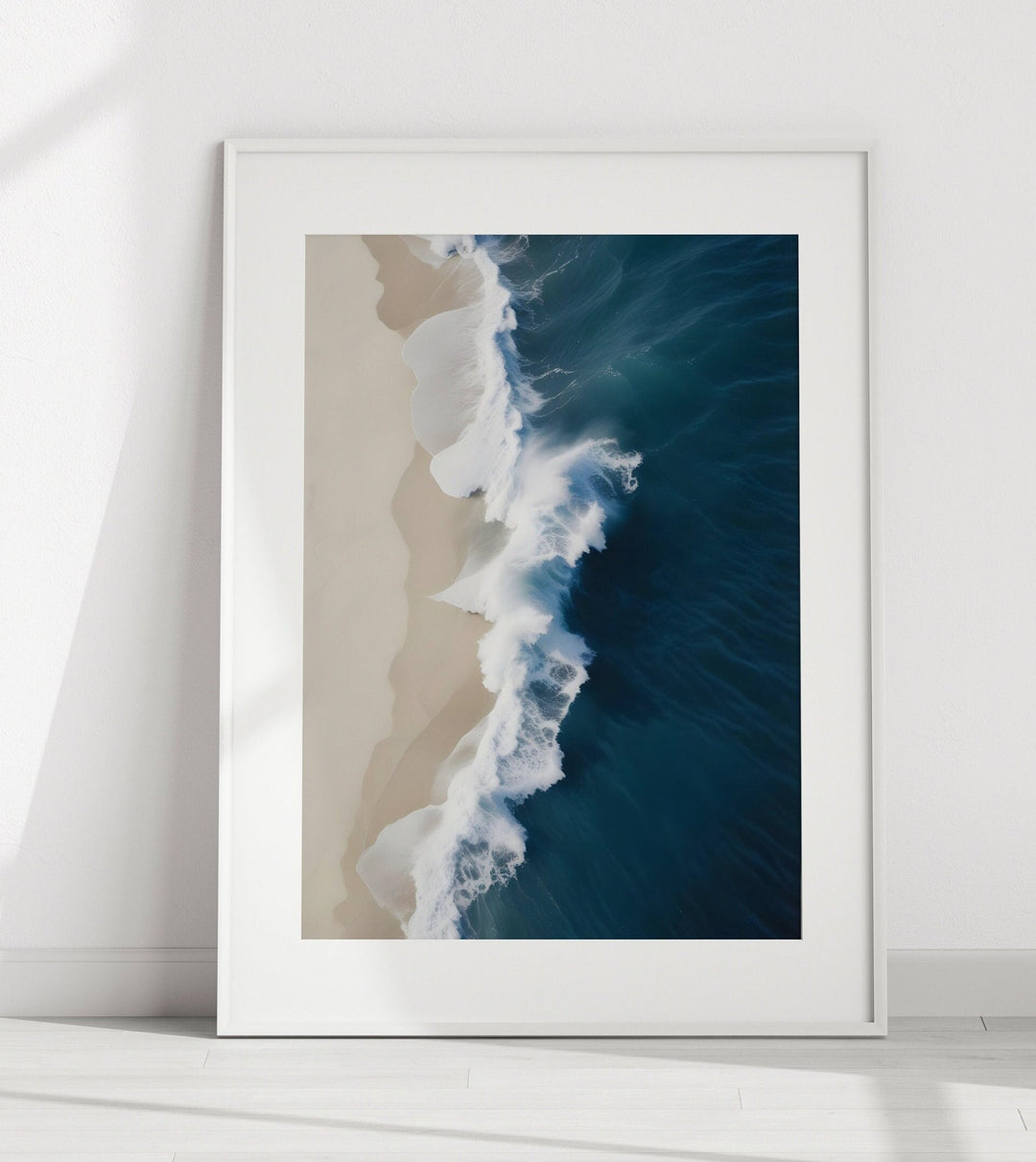 A framed photograph of a beach with waves crashing onto the shore, captured from an aerial perspective.
