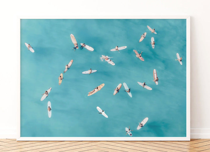 a group of surfers riding on surfboards in the ocean, with a blue sky and water background.
