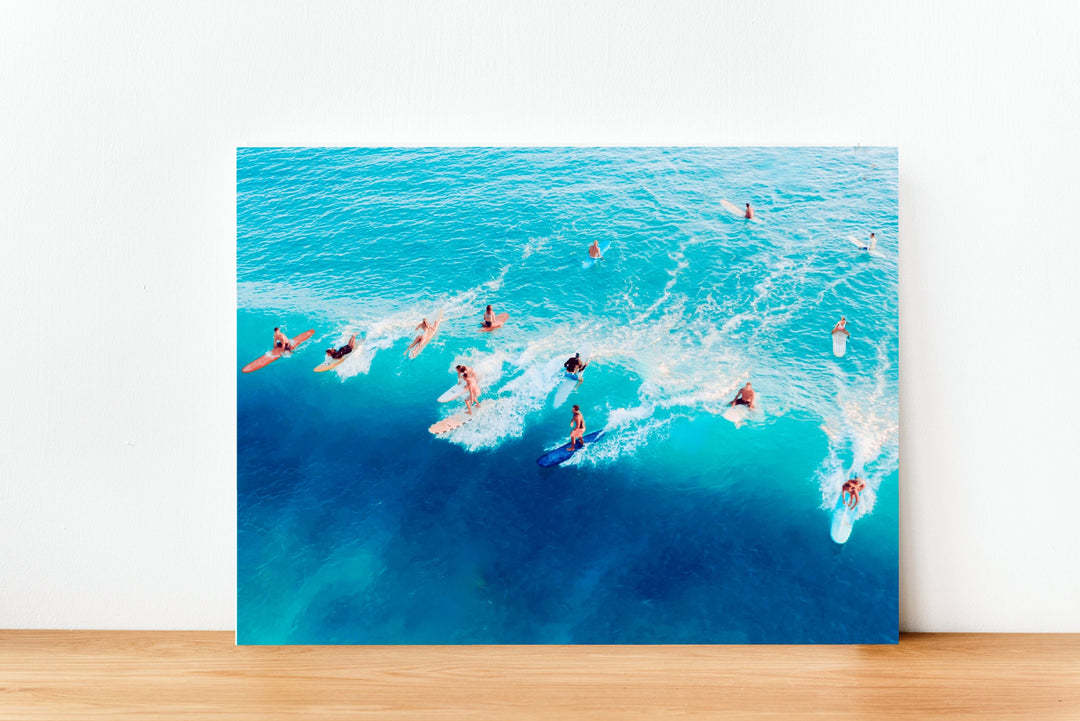 A group of people surfing on a sunny day, with waves breaking around them.